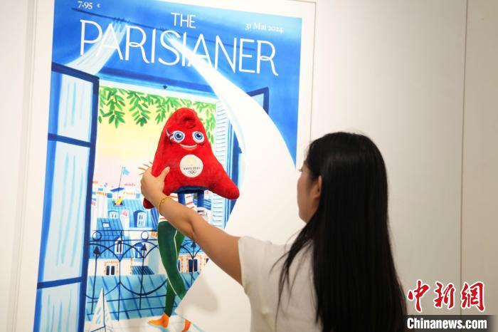 中国侨网7月26日，为迎接在法国巴黎举行的第33届夏季奥林匹克运动会，“中法文化之春——中法建交60周年特别呈现”项目——《巴黎人-城市中的运动》插画展在湖南长沙开展。展览以《巴黎人-城市中的运动》原画为设计灵感，40多幅插画作品，定格城市生活中运动悄然发生的每一个高光时刻，尤其是年轻人日渐畅销的社交方式。图为市民手持巴黎奥运会吉祥物在展厅打卡拍照。中新社记者 杨华峰 摄　 