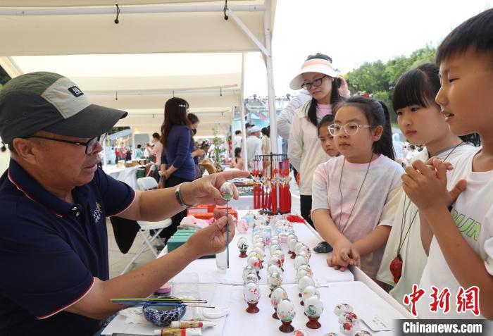 中国侨网6月18日,民众在宁夏银川市览山公园内观看鼻烟壶内画技艺。当日,数十位非遗代表性项目传承人为游客表演鼻烟壶内画、葫芦烙画等制作过程,吸引民众驻足观看。中新社记者 于晶 摄