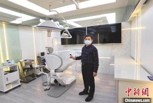 中国侨网吴伟正向中新网记者介绍口腔医院的设备。做种植牙手术时，医生可将高清晰度CT断层扫描投屏到手术室数个大屏幕上，节省了医生来回折返看CT的过程，缩短了手术时间。　朱晓颖　摄