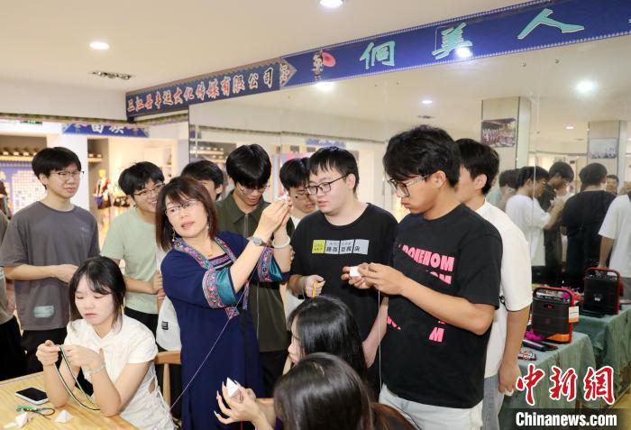 6月26日,广西科技大学50余名学生到三江侗族自治县县城大侗寨开展非遗研学活动,深入学习侗族吉祥花制作技艺,倾情体验侗乡非遗多彩魅力。图为学生在学习制作侗族吉祥花。龚普康 摄