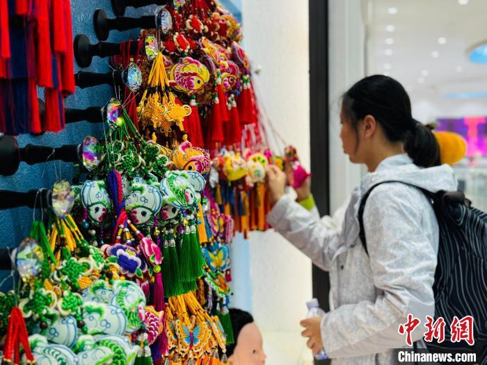 8月1日，2024澳门学生青海研学夏令营探访青海省海东市河湟新区青绣数字化经济总部，感受土族盘绣、湟源皮绣、河湟刺绣等非遗产品魅力，并与绣娘交流互动，了解非遗技艺的传承和保护。青海民间传统刺绣简称“青绣”。据悉，目前青海省青绣行业从业人数达30余万，青绣产业的发展有力促进了各族民众交往交流交融。图为澳门学生欣赏“青绣”香包。中新社记者 孙睿 摄