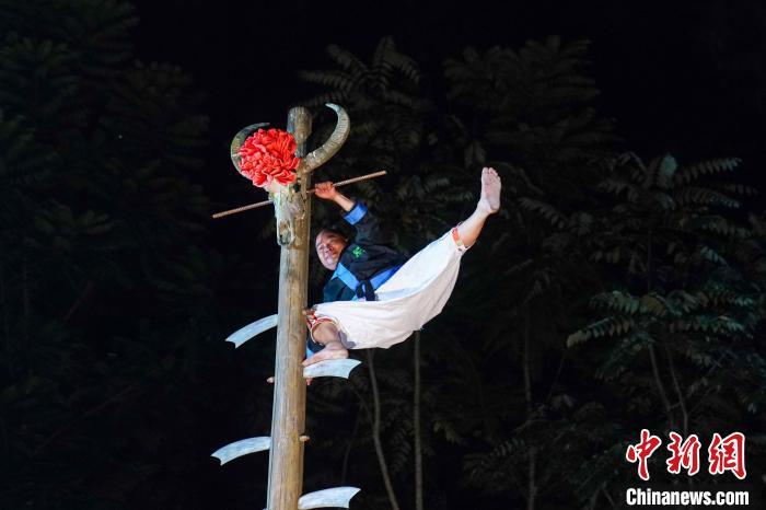 8月28日晚，广西河池市南丹县歌娅思谷景区，白裤瑶艺人东荣上演瑶族绝技“上刀山下火海”。瑶族是民风较为强悍的民族，他们在祭祀、祈福、驱邪的仪式中，往往要进行一系列的绝技神功，以显示所向无敌的气概。图为东荣在“刀山”上“大鹏展翅”。中新社记者 陈冠言 摄 