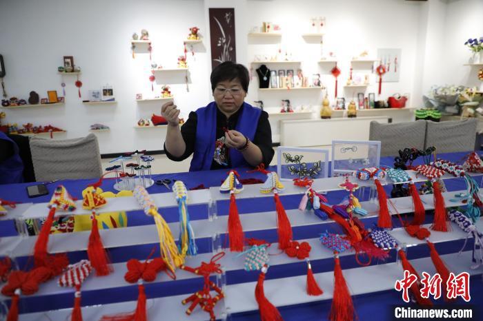 10月30日，在位于河北省张家口市阳原县的一家技艺工作室内，张家口市非物质文化遗产“钰姐盘扣技艺”传承人李家钰正在指导学员们制作盘扣，将色彩斑斓的丝线来回穿引、拉实，造型别致的盘扣作品慢慢呈现眼前。盘扣是中国传统服饰的重要元素之一，由远古结绳系带发展而来，沿用至今，包括盘、包、缝、编等多种手法。近年来，李家钰一直专注于传统盘扣技艺的保护与传承工作，常年开展技能培训，非遗助残扶残，累计免费培训学员上万人。图为李家钰正在制作盘扣。仝辉 摄