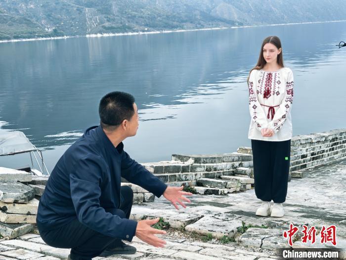 22岁的娜斯佳来自乌克兰，目前就读于河北大学。近日，她来到河北省承德市宽城满族自治县境内的潘家口水库，跟随当地长城保护员张卫东打卡独特的“水下长城”奇观。据了解，此段长城为明长城遗址，20世纪70年代因建设水利枢纽工程，部分长城隐没水下，从而形成“水下长城”景观。图为张卫东向娜斯佳讲解“水下长城”形成的原因。 袁宝利 摄 