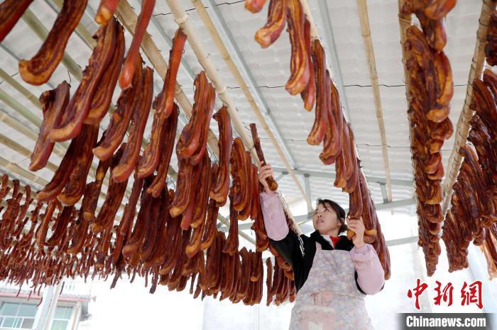 1月7日是中国传统节日腊八节,广西三江侗族自治县丹洲镇丹洲村迎来腊味销售旺季,当地民众抢抓时节赶制订单,忙着制作、晾晒、包装腊味,供应年货市场。丹洲村腊味产业链齐备,家家户户熟练掌握传统腊味制作工艺,当地腊味产品年销售额连续多年超过1000万元人民币。图为民众在制作腊味。龚普康 摄