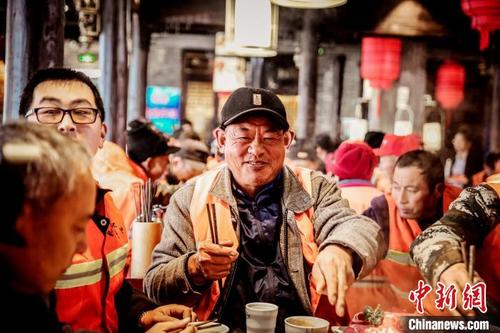 12月11日，山东省乳山市一家火锅店里暖意浓浓，数十名身穿橙色工作装的环卫工人在品尝热气腾腾的火锅。　乳轩　摄