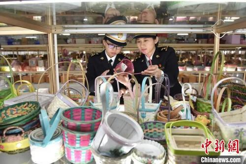 图为海关关员对待出口的竹木草制品进行检验。南宁海关供图