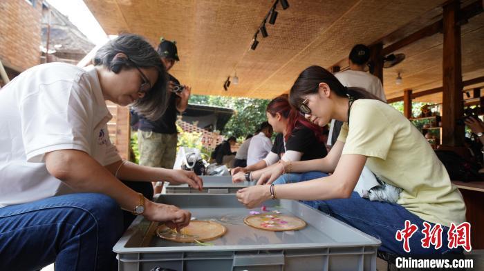千年傣寨曼远村、中国科学院西双版纳热带植物园、勐泐文化旅游区……5月30日至6月3日，第2届“彩云之约”海外台胞云南行活动在云南西双版纳傣族自治州开展。40余位海外台胞将在该州感受乡村振兴、民族团结、科技创新、生态文明成果，深度体验“有一种叫云南的生活”。图为5月31日，海外台胞走进曼远村体验鲜花造纸技艺。云南省台办 供图