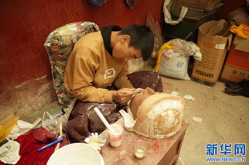 在西藏拉萨市达孜区，西洛的学徒旦增扎西在给面具塑形。（新华社/格桑边觉 摄）