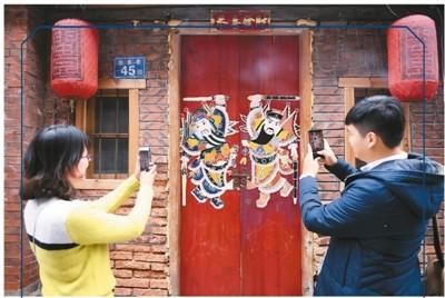 中国侨网图为两名游人在金鱼巷拍摄闽南传统民居大门上的门神图案。 新华社记者 林善传摄