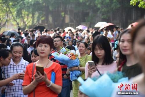 中国侨网资料图:高考临近结束,家长捧着鲜花在考场外等候孩子出现。 王以照 摄