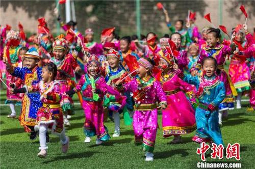 中国侨网图为7月23日，甘肃裕固族萌娃身着民族服装，挥动着鲜艳的五星红旗，表达对祖国热爱。　张小军　摄