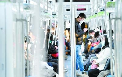 中国侨网2月10日，在地铁八通线，乘客明显增多，出行的人们都戴着口罩。当日是元宵节后上班第一天。本报记者 蔡代征摄