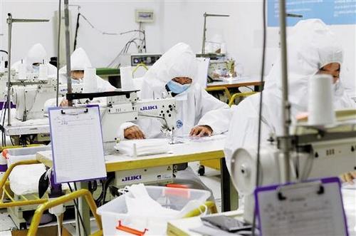 中国侨网浙江乔顿服饰股份有限公司临时腾出的无菌车间内，20多名工人正在缝制口罩。( 记者 张银燕 摄)