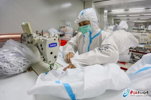 中国侨网柒牌工人专心致志地生产防护服。
