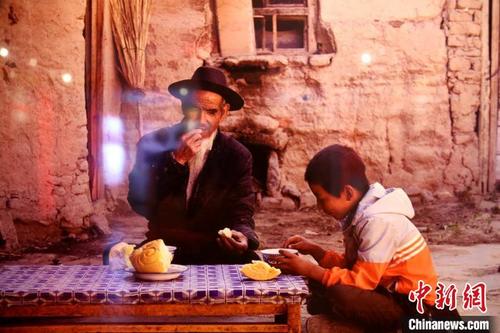 中国侨网图为记者翻拍的土族老汉吕有荣在老家生活情景的照片。　张添福　摄