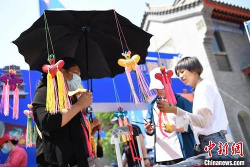 中国侨网端午节期间，甘肃“非遗+民俗”游受追捧。图为在假日期间举行的非遗节会上，游客挑选手工香包。杨艳敏 摄