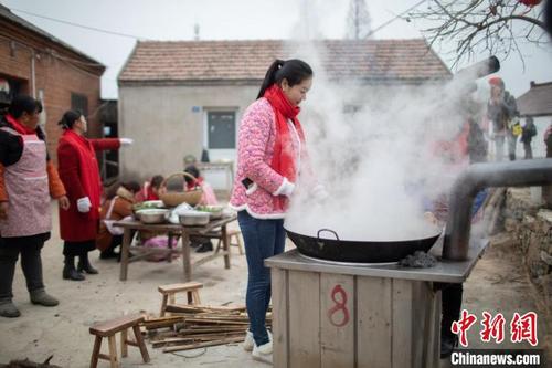中国侨网洪泽湖畔龟山村的男女老少聚集在一起，烧大锅菜，忙大年。　泱波　摄