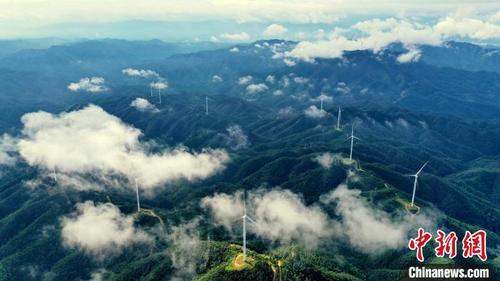 中国侨网蓝天白云之下，高耸的风力发电机组与连绵的青山共同构成了一幅夏日美景图。　朱海鹏　摄