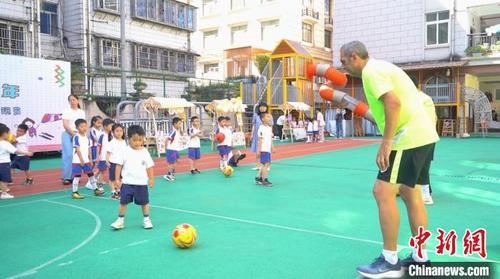 中国侨网西班牙HLK足球俱乐部教练与小朋友一起踢足球　孙云弋　摄