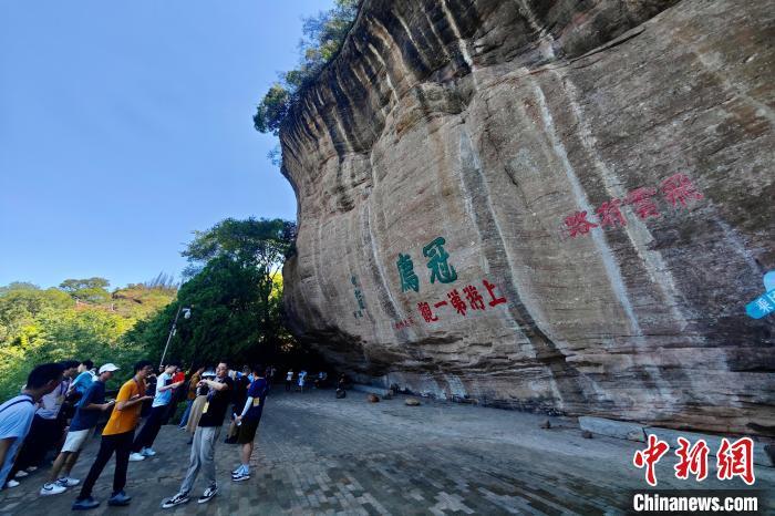 中国侨网8月5日,游客在福建连城冠豸山观看摩崖石刻。冠豸山属于丹霞地貌,其自然形态之美在于山之奇险与幽秀,被誉为“客家神山”。中新社记者 王东明 摄