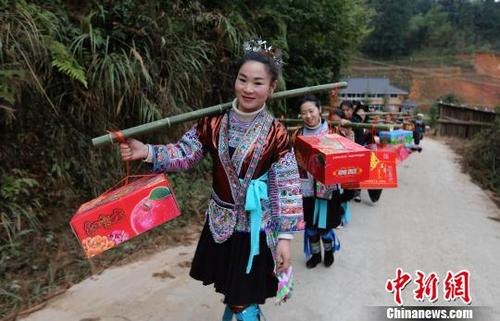 中国侨网送亲队伍带着新娘一起列队步行往新郎吴彦宣的家。　石峰　摄