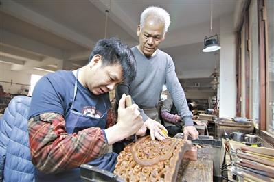 中国侨网胡敏强(右)在指导年轻人雕刻红木。