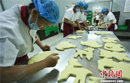 中国侨网9月18日，在甘肃张掖一家超市的主食加工车间，工作人员在制作“土月饼”。　王将　摄