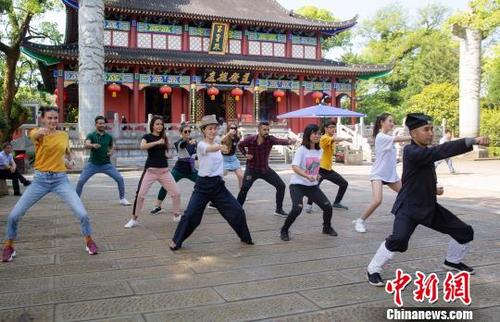 中国侨网留学生在江西鹰潭龙虎山天师府前，跟着道长学太极拳，感悟道家文化。　吴志成　摄
