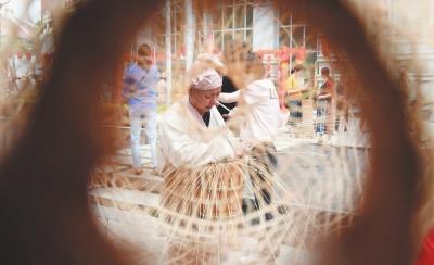 中国侨网第十四届莆田艺博会上，手艺人在制作竹编工艺品。