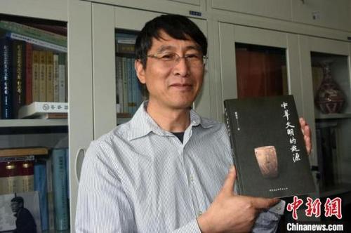 中国侨网韩建业教授在办公室展示《中华文明的起源》新书。　中新社记者 孙自法　摄