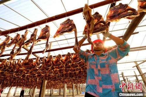 中国侨网图为江西大余的工人们对板鸭的造型进行调整处理 叶功富 摄