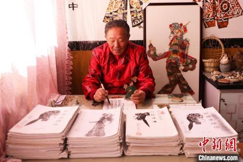 中国侨网唐山皮影艺人李绍民在家里创作皮影戏剧本。　朱大勇　摄
